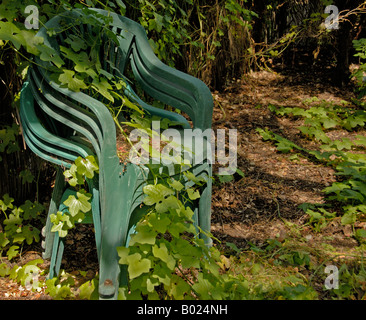Sedie in giardino nel cortile impilati con ricoperta di edera nel bel sole primaverile e ombra. Foto Stock