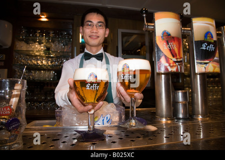 Barman cinese serve un belga Leffe birra in Le Roy d'Espagne bar. La Grand Place di Bruxelles. Belgio Foto Stock