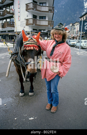 Una giovane donna con il suo cavallo e carro nel centro di Chamonix Francia una popolare località sciistica nelle Alpi Foto Stock