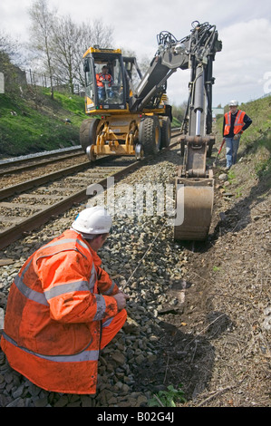 Specialista contraente utilizzando road-veicoli ferroviari a scavare e sostituire obsoleti via sistema di drenaggio su una trafficata della rete ferroviaria. Foto Stock