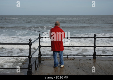 Un pescatore solitario sul lungomare in Scarborough North Yorkshire Foto Stock