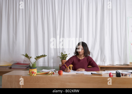 Indiano insegnante femmina iscritto alla scrivania Foto Stock