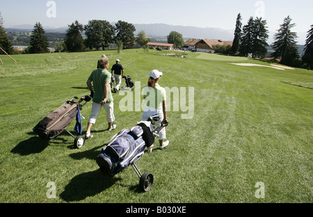 Volo di tre golfisti con golf cart sul fairway Gsteig,Baviera avvicinando la clubhouse. Foto Stock