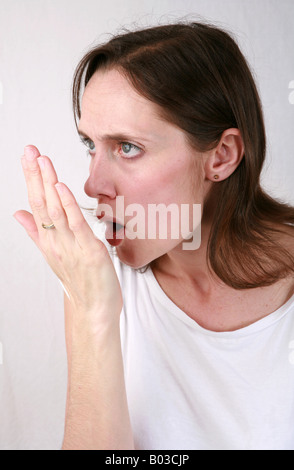 Giovane donna si respira sul palmo della mano per controllo alito cattivo alitosi stantio maleodoranti respiro personale di scarsa igiene orale Foto Stock