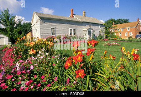 Fiori in un giardino insieme fuori una bella ma vecchia casa residenziale nell'Amana colonie nel paese di fattoria di Iowa Foto Stock