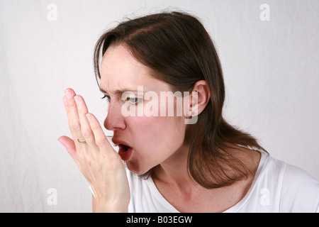 Giovane donna si respira sul palmo della mano per controllo alito cattivo alitosi stantio maleodoranti respiro personale di scarsa igiene orale Foto Stock