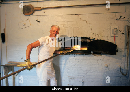 Un baker prende una pagnotta di pane fresco dal suo grande forno a una panetteria nell'Amana colonie in fattoria paese dell America Centrale Foto Stock