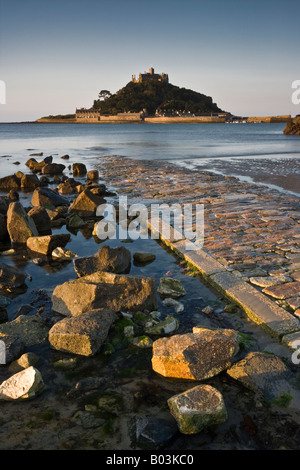 Rock, flotsam e il percorso che conduce a un sole bagnata St Michael's Mount, Cornwall, Inghilterra Foto Stock