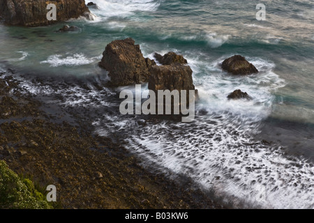 Affioramento di rocce con onde che sopraggiungono nell'Isola del Sud della Nuova Zelanda Foto Stock