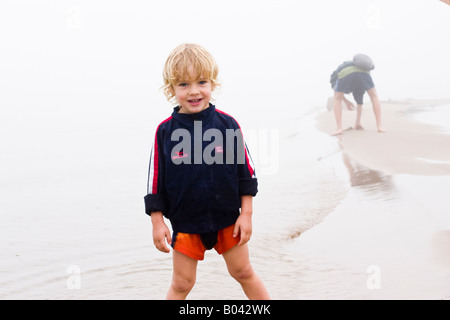 Ragazzo biondo sulla spiaggia misty, Lielupe, Lettonia Foto Stock