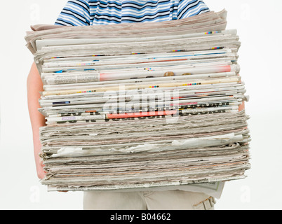 Ragazzo che porta una pila di quotidiani Foto Stock