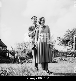 Vecchia famiglia vintage fotografia istantanea di un uomo e di una donna in piedi nel giardino della famiglia Foto Stock