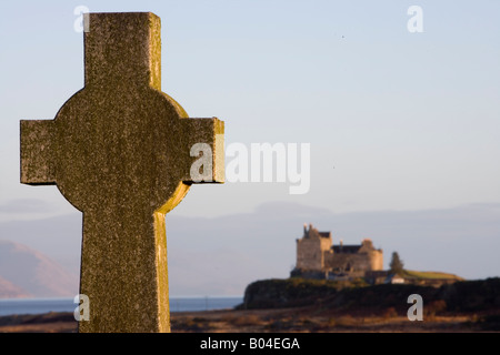 Croce celtica nel cimitero, con il Castello di Duart dietro, Isle of Mull, Scozia Foto Stock