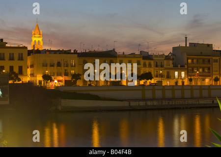 Guardando oltre il Rio Guadalquivir (fiume) verso il quartiere di Triana e la torre campanaria di Iglesia de Santa Ana al crepuscolo Foto Stock