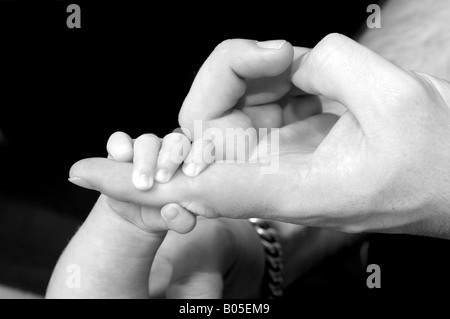 Bambinos mano giacente in mano dei padri Foto Stock