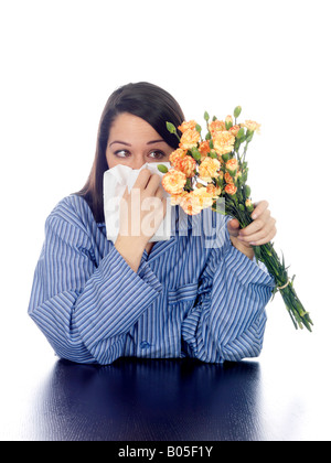 Giovane donna in pigiama con hayfever holding fiori modello rilasciato Foto Stock