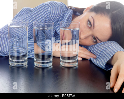 Giovane donna in pigiama con bicchieri di acqua modello rilasciato Foto Stock