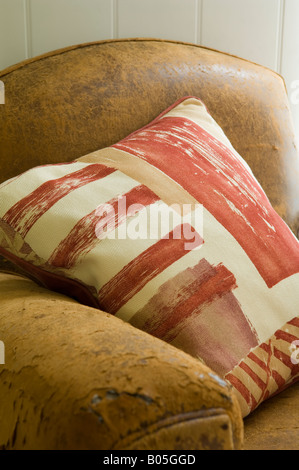 Cuscino su distressed sedia in pelle con design di tessuto da Jim Thompson Foto Stock
