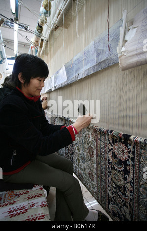 Mani veloci rendono un tappeto in un tappeto di seta in fabbrica a Pechino, in Cina. Foto Stock