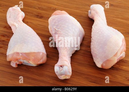 Il pollo crudo bacchette su un tagliere di legno Foto Stock