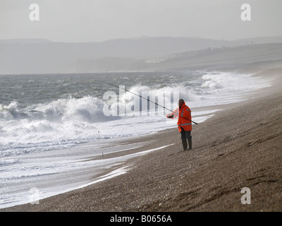 Pescatore solitario sulla spiaggia ondulata Foto Stock