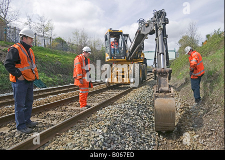 Specialista contraente utilizzando road-veicoli ferroviari a scavare e sostituire obsoleti via sistema di drenaggio su una trafficata della rete ferroviaria. Foto Stock