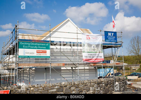 Anglesey North Wales UK nuovi eco friendly case in vendita con agente immobiliare s segno su ponteggi sul sito di costruzione Foto Stock
