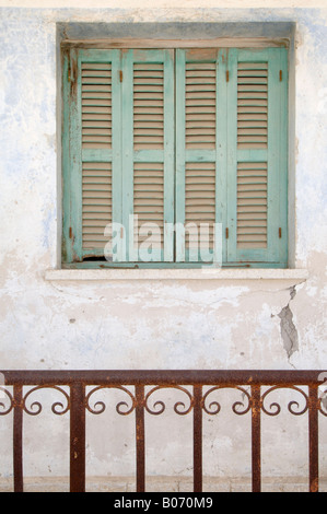 Verde sfumato persiane sfinestrato in una parete dietro la ruggine parapetti decorati nel tradizionale villaggio di Polemi, Paphos, Cipro Foto Stock