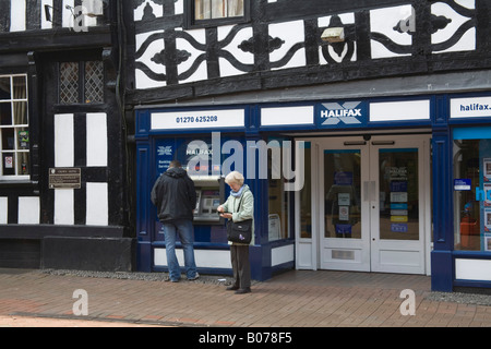 Cheshire England Regno Unito aprile uomo prendendo denaro fuori di una banca bancomat una donna in attesa Foto Stock