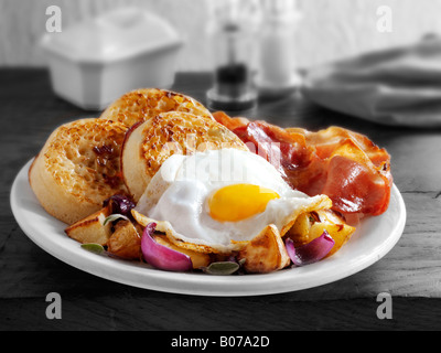 La completa prima colazione inglese con cialdine, servita su una piastra bianca in una tabella - uova fritte, pancetta, sauté di patate e cialdine Foto Stock