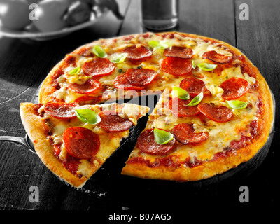 Crosta di pioggia salsiccia per pizza pizza con una fetta fuori Foto Stock