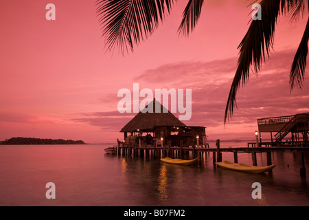 Panama, Bocas del Toro Provincia, Carenero Isola (Isla Carenero), decapato pappagallo Ristorante e bar si riflette nell'oceano al tramonto Foto Stock