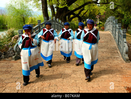 Un gruppo di minoranza Naxi donne attraversando un ponte a Lijiang il Drago Nero parco piscina. Foto Stock