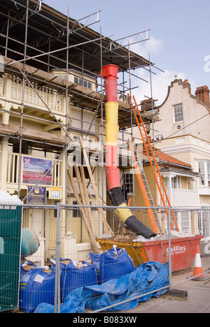 Scivolo di spazzatura sul sito di costruzione prendendo i rifiuti in un saltare in fondo nel Regno Unito Foto Stock