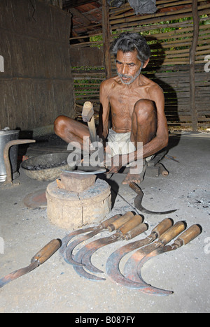 Fabbro tribale martellare per dare forma al ferro da stiro. Warli tribe, Thane, Maharashtra, India Foto Stock