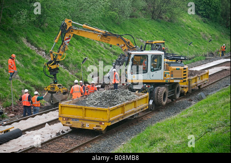 Specialista contraente utilizzando road-veicoli ferroviari a scavare e sostituire obsoleti via sistema di drenaggio su una trafficata della rete ferroviaria. Foto Stock