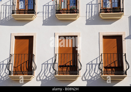 Windows con open e persiane chiuse dietro di ringhiere in ferro battuto su una facciata di edificio nel centro storico di La Nucia, Ali Foto Stock