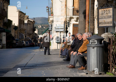 Gli anziani seduti sul lato di una strada a Noto, Sicilia, Italia Foto Stock