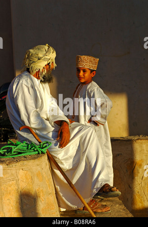 Padre e figlio di parlare, indossando il tradizionale Omani abbigliamento, Nizwa, Oman, Medio Oriente Foto Stock