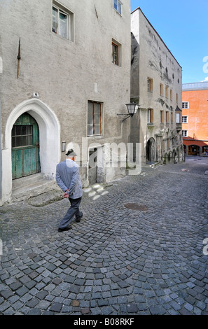 Il vecchio uomo che cammina giù il vicolo di ciottoli nel centro storico di Hall in Tirolo, Austria Foto Stock