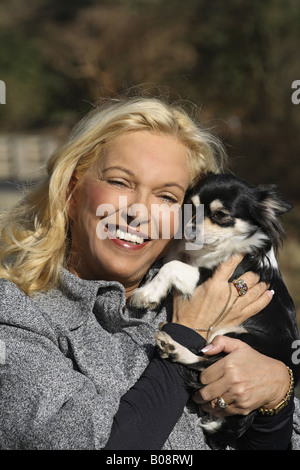 Chihuahua (Canis lupus f. familiaris), biondo donna con capelli lunghi Chihuahua nelle sue braccia Foto Stock