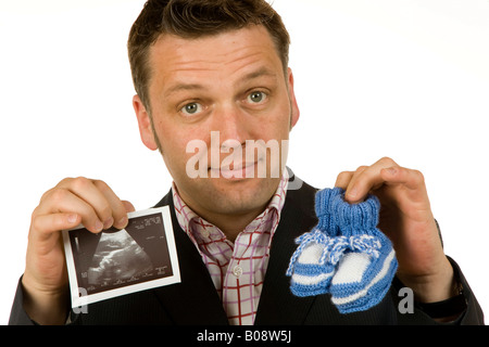 Il 40-anno-vecchio uomo d affari azienda scarpe per bambini e di una immagine ad ultrasuoni Foto Stock