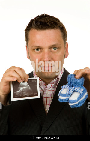 Il 40-anno-vecchio uomo d affari azienda scarpe per bambini e di una immagine ad ultrasuoni Foto Stock