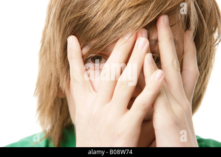 13-anno-vecchio ragazzo che copre il viso con le mani Foto Stock