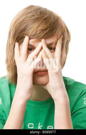 13-anno-vecchio ragazzo che copre il viso con le mani Foto Stock