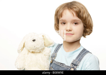 Biondo scuro 8-anno-vecchia ragazza tenendo un peluche, il giocattolo di peluche Foto Stock