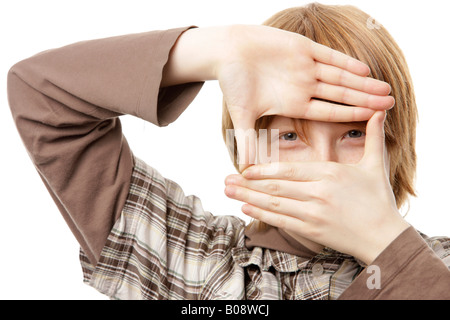 12-anno-vecchio ragazzo tiene le mani davanti al suo volto Foto Stock