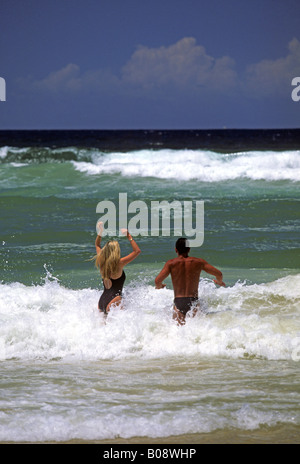 Giovane jumping nelle onde a Surfers Paradise Beach, Gold Coast, Queensland, Australia Foto Stock