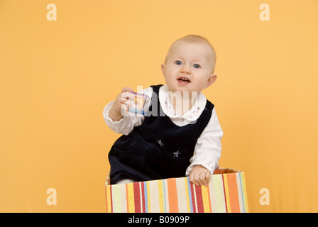 Bambino con rattle in piedi in una scatola Foto Stock