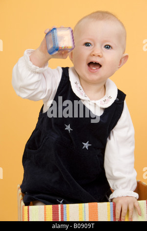 Bambino con rattle in piedi in una scatola Foto Stock